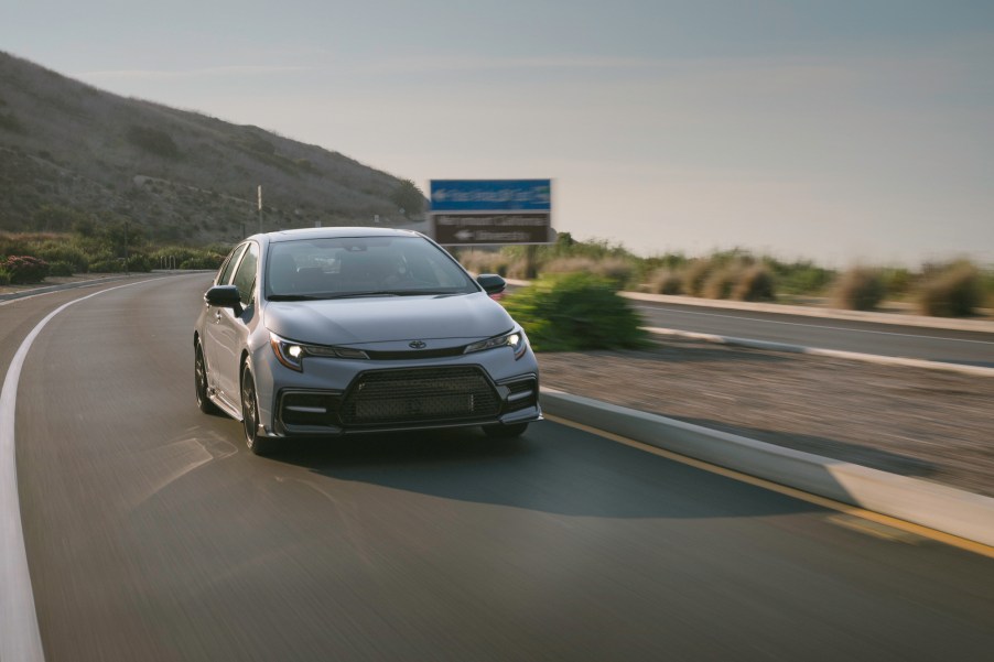 A silver 2021 Toyota Corolla Apex compact car cornering on a mountain highway