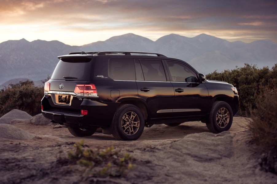 A black 2021 Toyota Land Cruiser full-size SUV parked on rocky terrain overlooking mountains