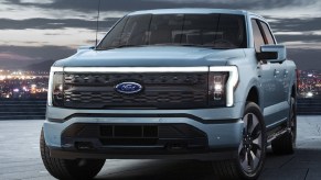 The front 3/4 view of a light-blue 2022 Ford F-150 Lightning on a parking-garage roof in a city