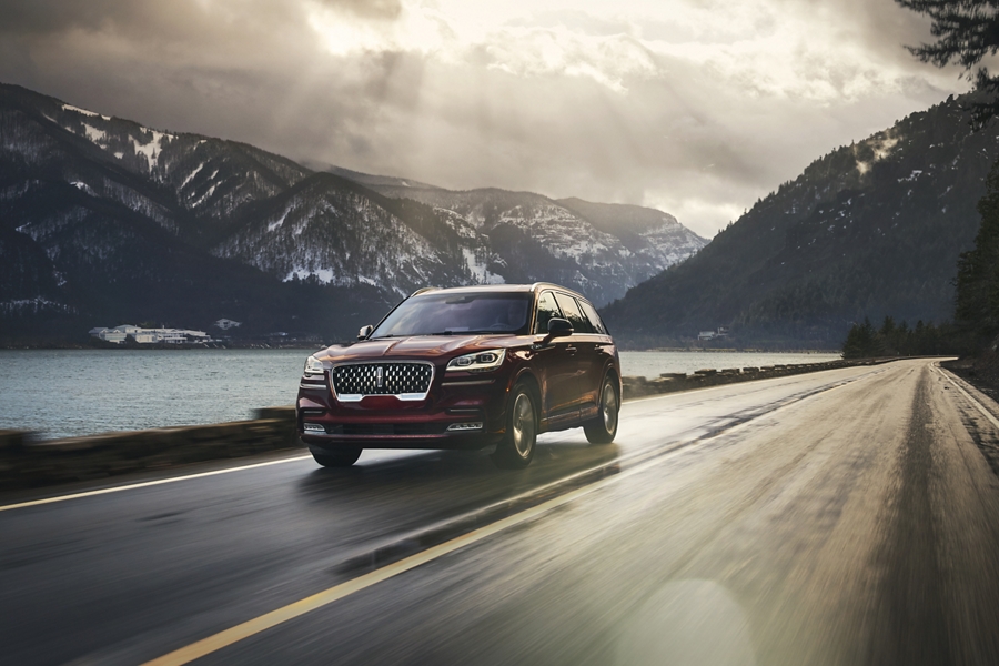 The 2021 Lincoln Aviator PHEV driving down a road near water and mountains