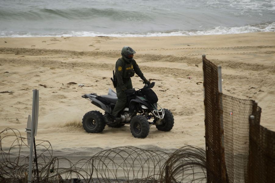 A U.S. Border Patrol agent drives an ATV on the beach next to the Pacific Ocean