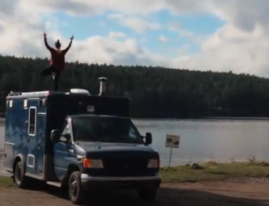 Amanda doing tree pose on the roof deck of her Ford E-350 ambulance camper van