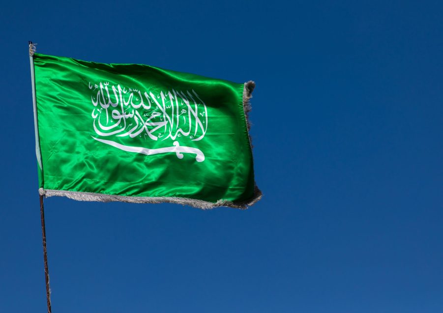 Emerald green flag of Saudi Arabia against a blue sky