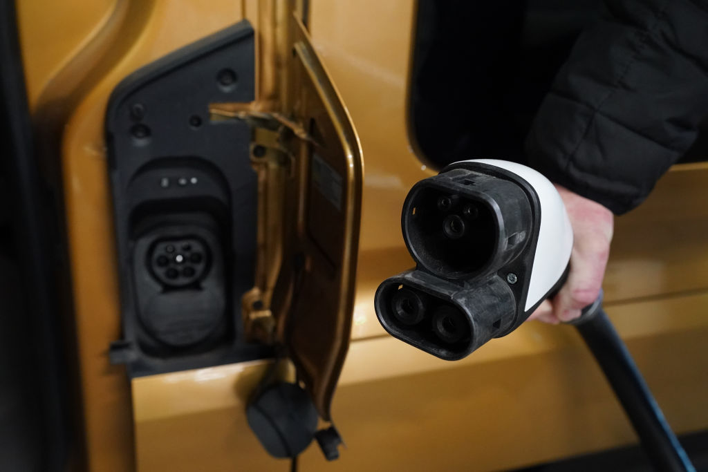 A man unplugs an EV from its charger.