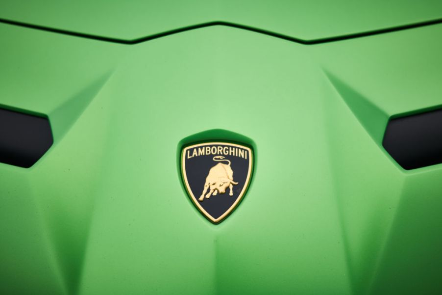 closeup shot of Lamborghini logo on hood of green Aventador