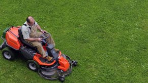 a man mowing a pristine lawn with a lawn tractor