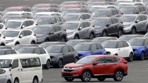 A red Honda Motor Co. CR-V sports utility vehicle (SUV) bound for shipment, bottom right, is driven while others sit parked at a port in Yokohama, Kanagawa Prefecture, Japan