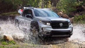 A silver 2021 Honda Ridgeline splashes through a puddle.