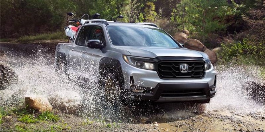 A silver 2021 Honda Ridgeline splashes through a puddle.