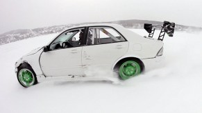 A modified white Lexus IS300 sedan drifting on a frozen lake