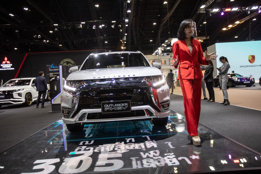 A model stands next to a silver Mitsubishi Outlander PHEV at the Mitsubishi stand during the 42nd Bangkok International Motor Show