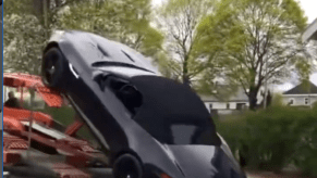 An iamge of a Jaguar F-Type falling from a trailer and crashing into a pickup truck.