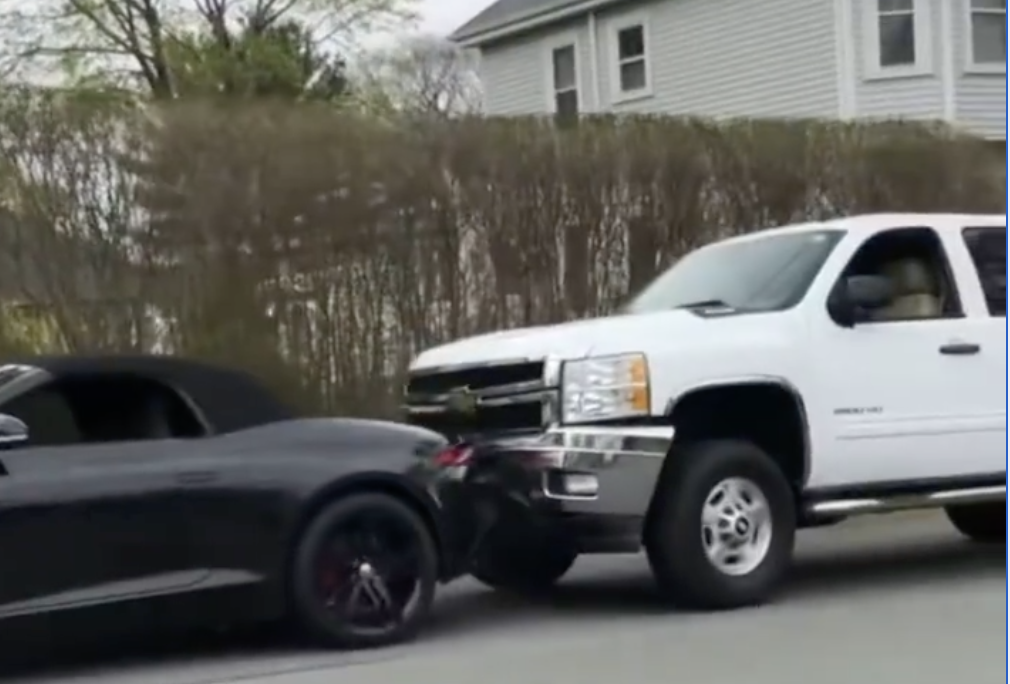 An iamge of a Jaguar F-Type falling from a trailer and crashing into a pickup truck.