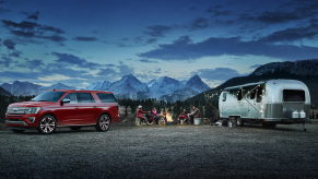 A red 2021 Ford Expedition parked at a campsite with an Airstream trailer