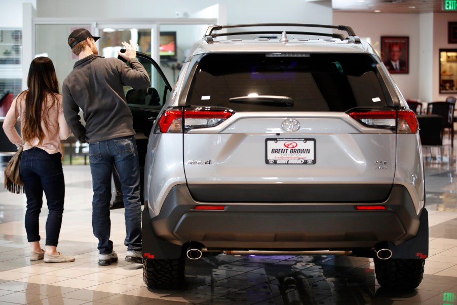 Potential customers look at a silver Toyota Motor Corp. RAV4 sport utility vehicle (SUV) at the Brent Brown Toyota dealership