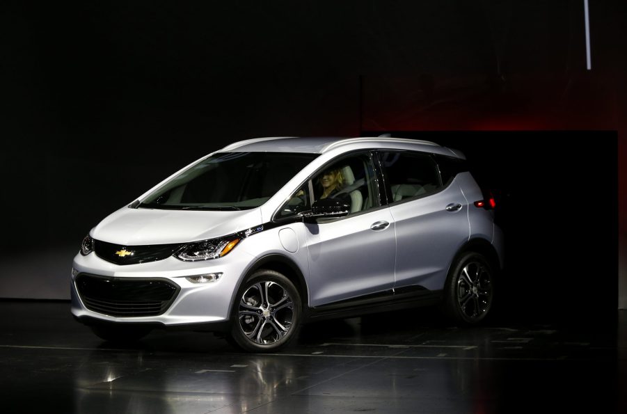 A silver Chevy Bolt under a lightbox at an auto show