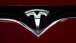 a chrome Tesla emblem on a red EV