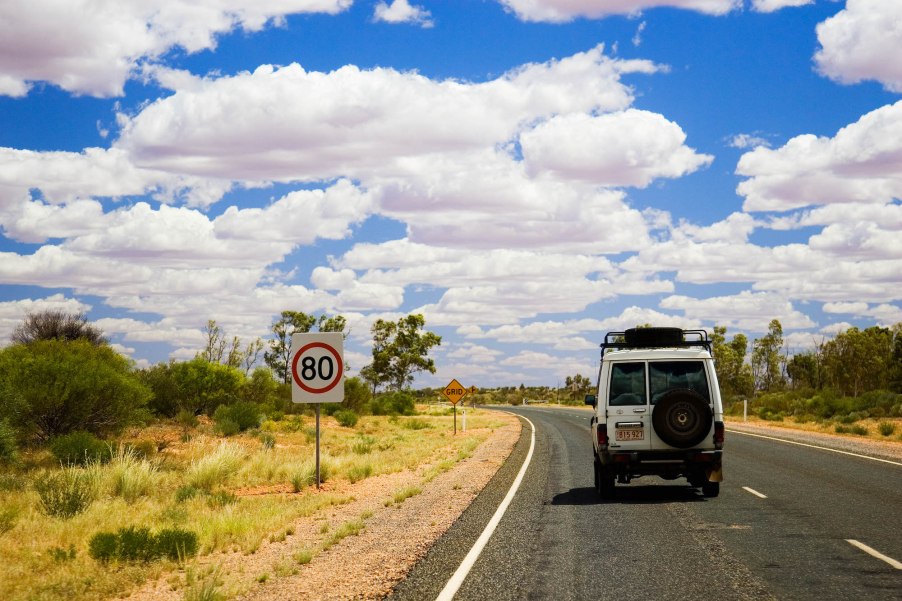 An SUV travels on the left-hand side of the road in the Australian outback