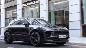 A black Porsche Macan sits outside a shop on the street in London