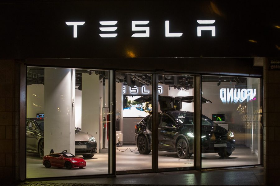 A black Tesla Model X on display in a showroom at night