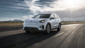 A white Kia Niro rolls down the road