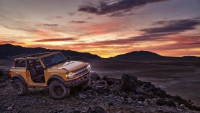 A yellow Ford Bronco off road at sunset