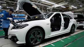 A worker assembles a white Toyota Crown sedan on the production line of the company's Motomachi factory on July 30, 2018, in Toyota, Japan