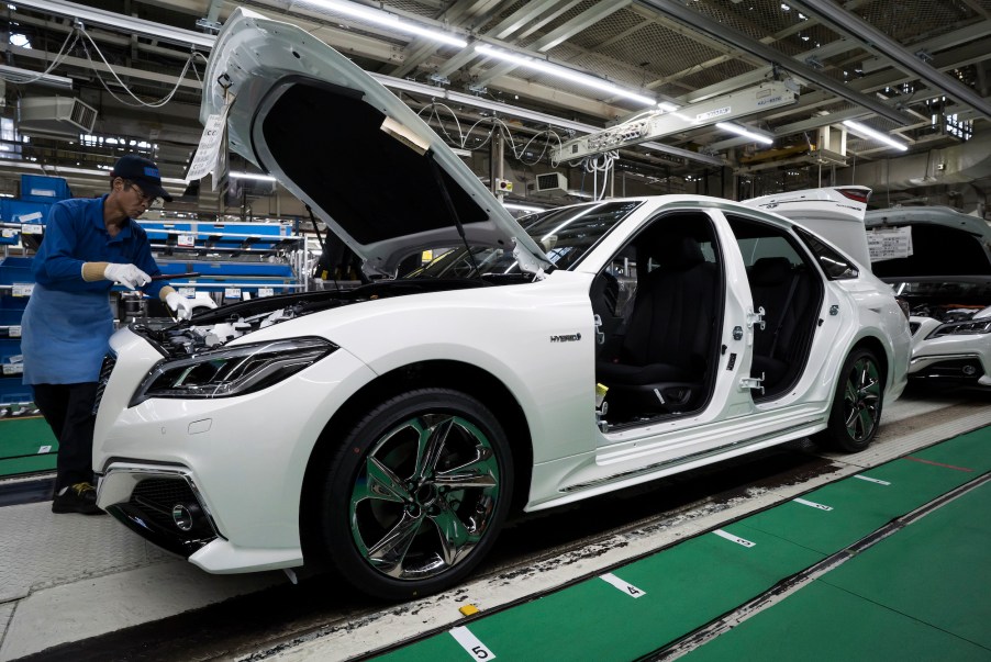 A worker assembles a white Toyota Crown sedan on the production line of the company's Motomachi factory on July 30, 2018, in Toyota, Japan