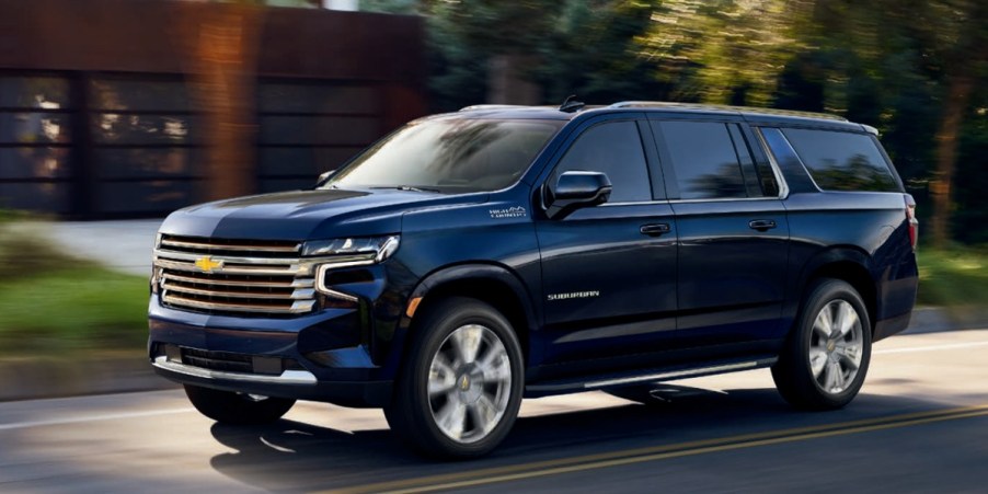 A blue 2021 Chevrolet Suburban full-size SUV is driving on the road.