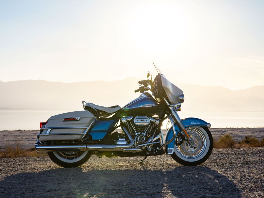 The side view of a blue-and-white 2021 Harley-Davidson Electra Glide Revival on a rocky beach