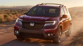 A red 2021 Honda Passport driving on a dirt road