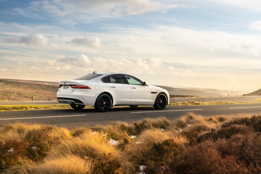 A white 2021 Jaguar XF luxury sedan stopped on a two-lane highway through arid plains