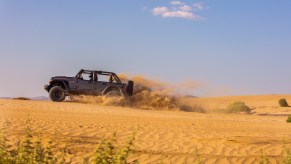 The 2021 Jeep Wrangler easily navigates a sand dune and is great for beach adventures