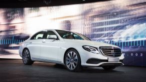 A white 2021 Mercedes-Benz E-Class sedan parked on a stage at an auto show