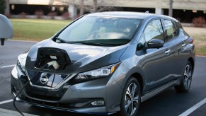 A dark-gray metallic 2021 Nissan Leaf in a parking space at a charging station