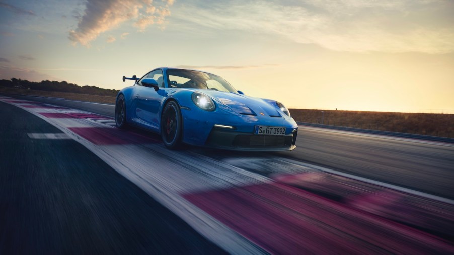 A blue 2021 Porsche 911 driving around a track, the 911 is the best new sports car for road trips