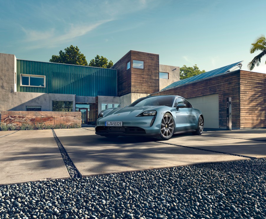 A light-blue 2021 Porsche Taycan electric sports car parked outside a modern home