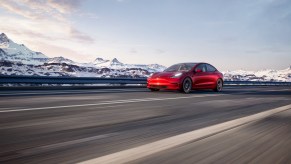 A red 2021 Tesla Model 3 driving, the Model 3 is one of the best EVs with over 100 MPGe