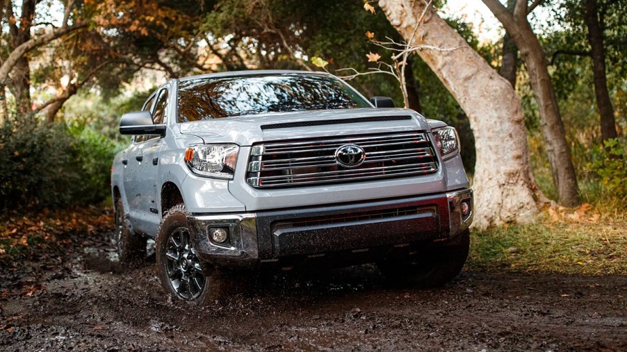 An ice gray 2021 Toyota Tundra splashes through mud.