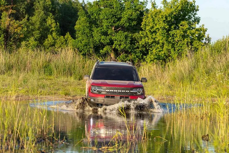 a red 2021 Ford Bronco driving through shallow water