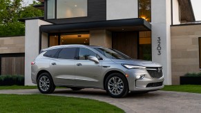 A silver 2022 Buick Enclave Avenir luxury midsize SUV parked in front of a modern house