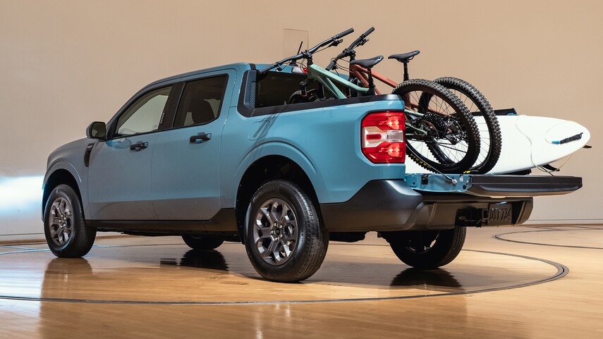 a blue 2022 ford maverick with bikes and a surf board in the bed