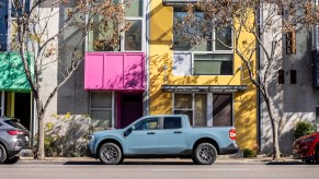 A powder-blue 2022 Ford Maverick Hybrid XLT pickup truck paked on a city street outside a colorful building