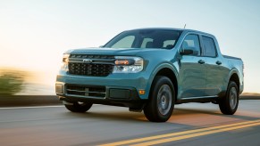 A powder-blue 2022 Ford Maverick Hybrid XLT compact pickup truck travels on a two-lane highway