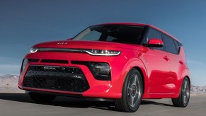 A red 2022 Kia Soul driving on a desert road