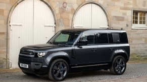 A black 2022 Land Rover Defender V8 parked by a tan stone building