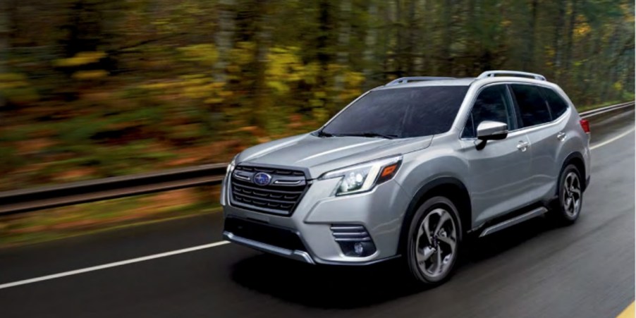 A gray 2022 Subaru Forester small SUV is driving on the road.