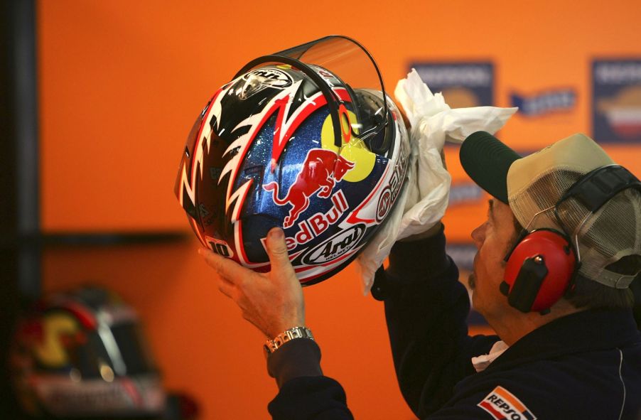 A Repsol Honda MotoGP mechanic cleaning a motorcycle helmet for Nicki Hayden at the 2006 Shanghai GP