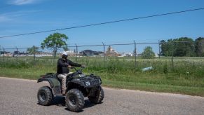 A man drives an ATV on a street through a neighborhood in McIntosh, Alabama, on April 12, 2021