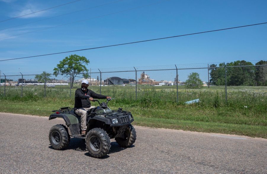 A man drives an ATV on a street through a neighborhood in McIntosh, Alabama, on April 12, 2021